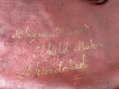 Lot 20 - AN INDIAN HIDE SHIELD (DHAL), 19TH CENTURY, SIGNED BHAGUAN KHOOSALOA, AHMEDABAD