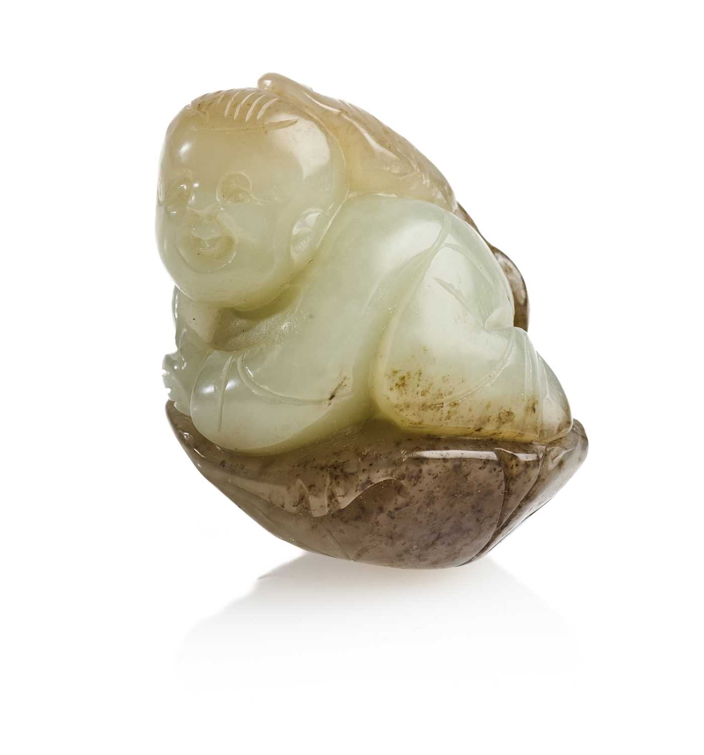 Lot 69 - A CHINESE CELADON AND BROWN JADE CARVING OF A BOY AND LOTUS, QING DYNASTY (1644-1911)