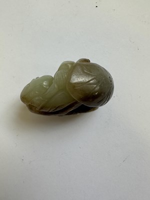 Lot 69 - A CHINESE CELADON AND BROWN JADE CARVING OF A BOY AND LOTUS, QING DYNASTY (1644-1911)
