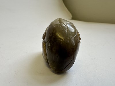 Lot 69 - A CHINESE CELADON AND BROWN JADE CARVING OF A BOY AND LOTUS, QING DYNASTY (1644-1911)
