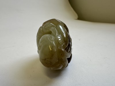 Lot 69 - A CHINESE CELADON AND BROWN JADE CARVING OF A BOY AND LOTUS, QING DYNASTY (1644-1911)