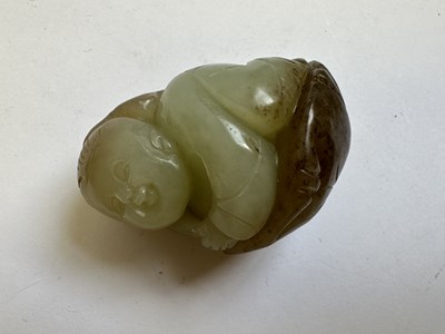Lot 69 - A CHINESE CELADON AND BROWN JADE CARVING OF A BOY AND LOTUS, QING DYNASTY (1644-1911)