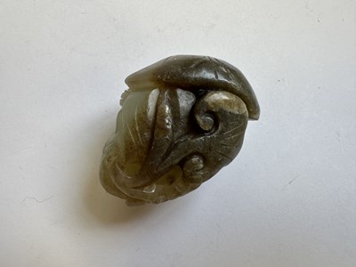 Lot 69 - A CHINESE CELADON AND BROWN JADE CARVING OF A BOY AND LOTUS, QING DYNASTY (1644-1911)