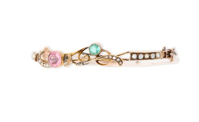 Lot 43 - EDWARDIAN GOLD, TOURMALINE AND HALF-PEARL HINGED BANGLE, 1909
