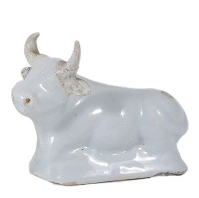 Lot 10 - A SMALL DUTCH DELFT FIGURE OF A RECUMBENT COW