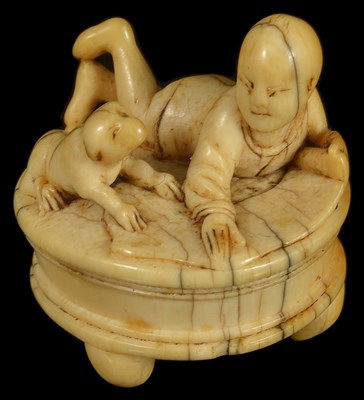 Lot 403 - ~A JAPANESE IVORY NETSUKE OF A BOY AND PUP