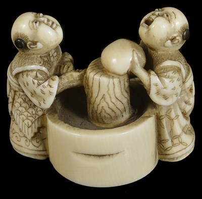 Lot 413 - ~A JAPANESE IVORY NETSUKE OF BOYS MAKING MOCHI