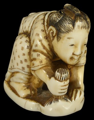 Lot 431 - ~A JAPANESE IVORY NETSUKE OF A MAN POLISHING