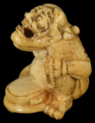 Lot 443 - ~A JAPANESE IVORY NETSUKE OF A PENITENT ONI