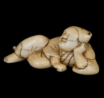 Lot 455 - ~AN IVORY NETSUKE OF A SLEEPING MONKEY TRAINER