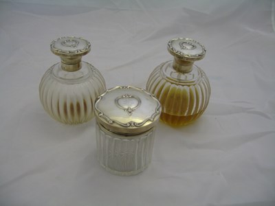 Lot 80 - A PAIR GEORGE V SILVER-MOUNTED PERFUME BOTTLES AND A TOILET JAR